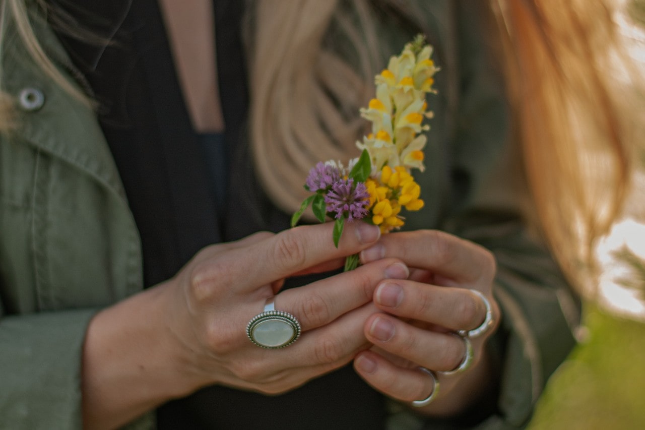 a  woman wearing rings holds wildflowers.