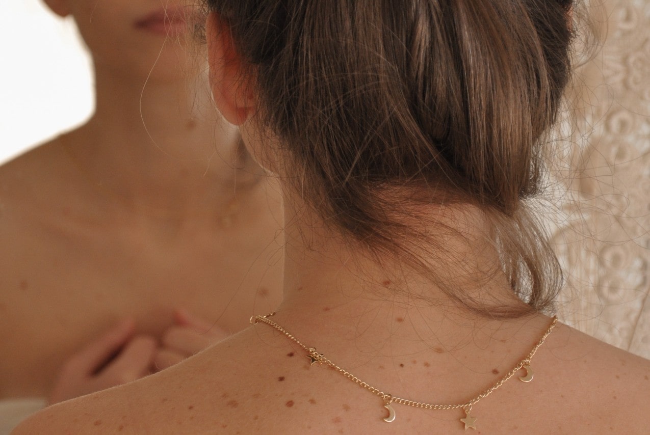 a posterior view of a woman wearing a yellow gold station necklace