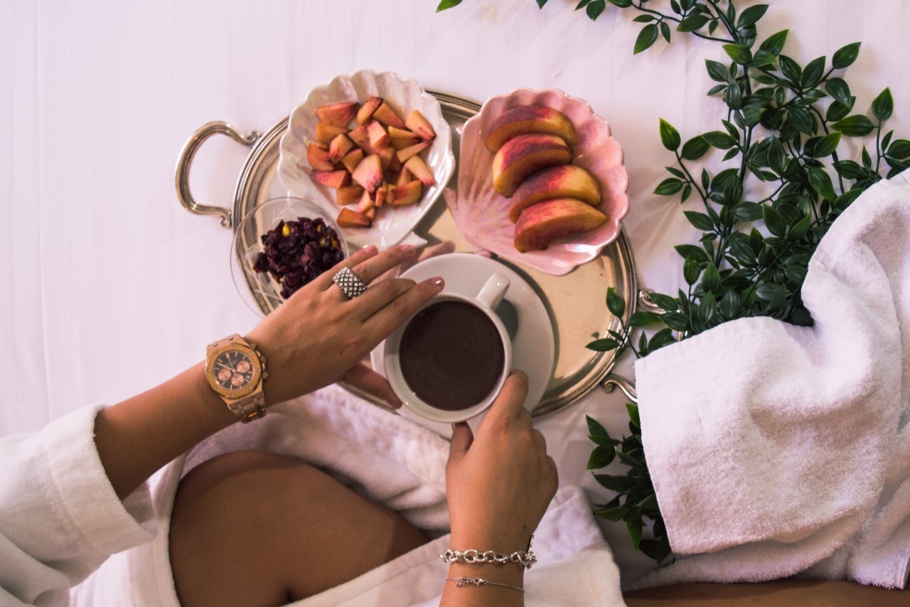 woman drinking coffee with watch on bed