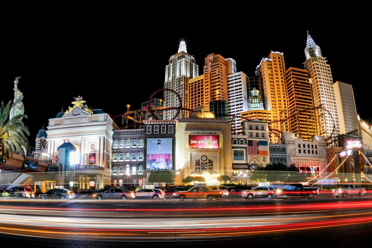 A picture of Las Vegas city center, featuring skyscrapers, casinos, roller coasters, and moving cars on the road.