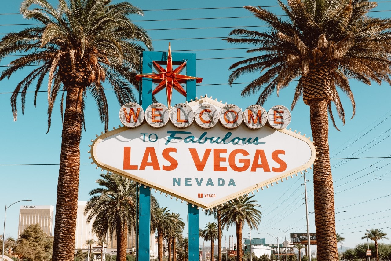 A view of the “Welcome to Fabulous Las Vegas” sign between two palm trees.