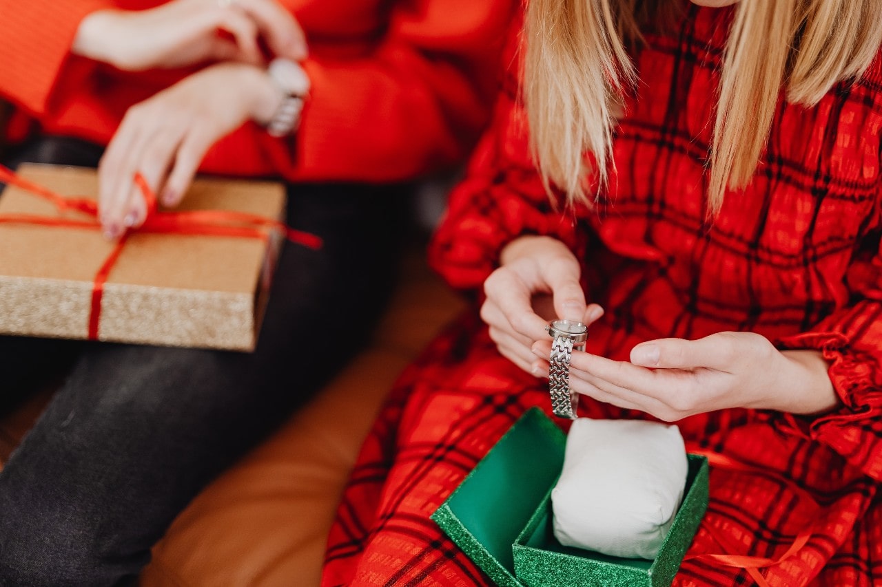 two women sitting and opening gift boxed containing silver watches