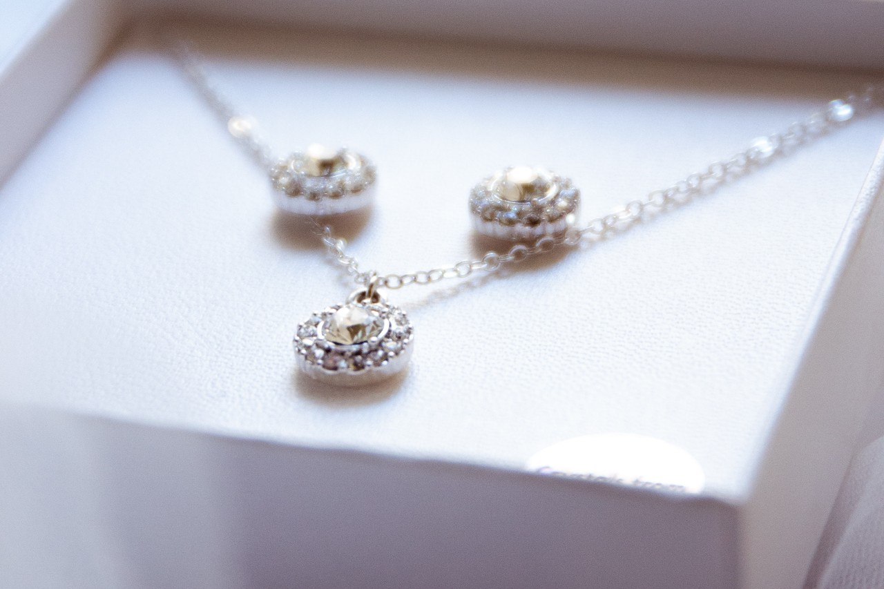 a matching set of diamond pendant necklace and stud earrings in a white box