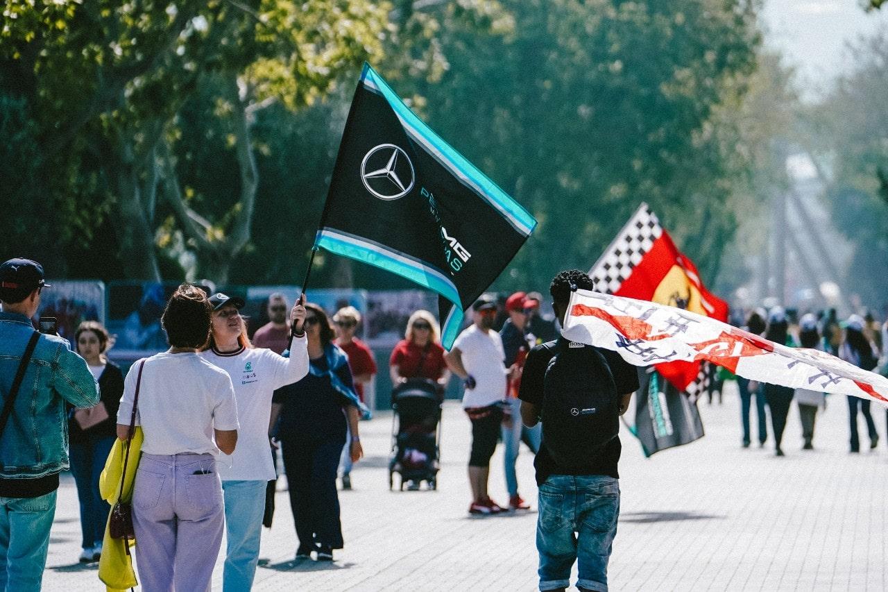 a crowd waving flags and walking towards a Formula 1 race