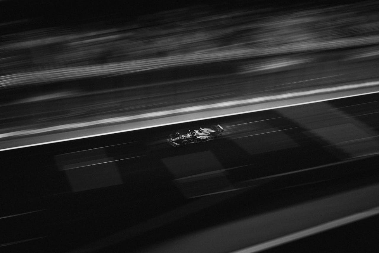 A black and white action shot of a Formula One car speeding down the track.
