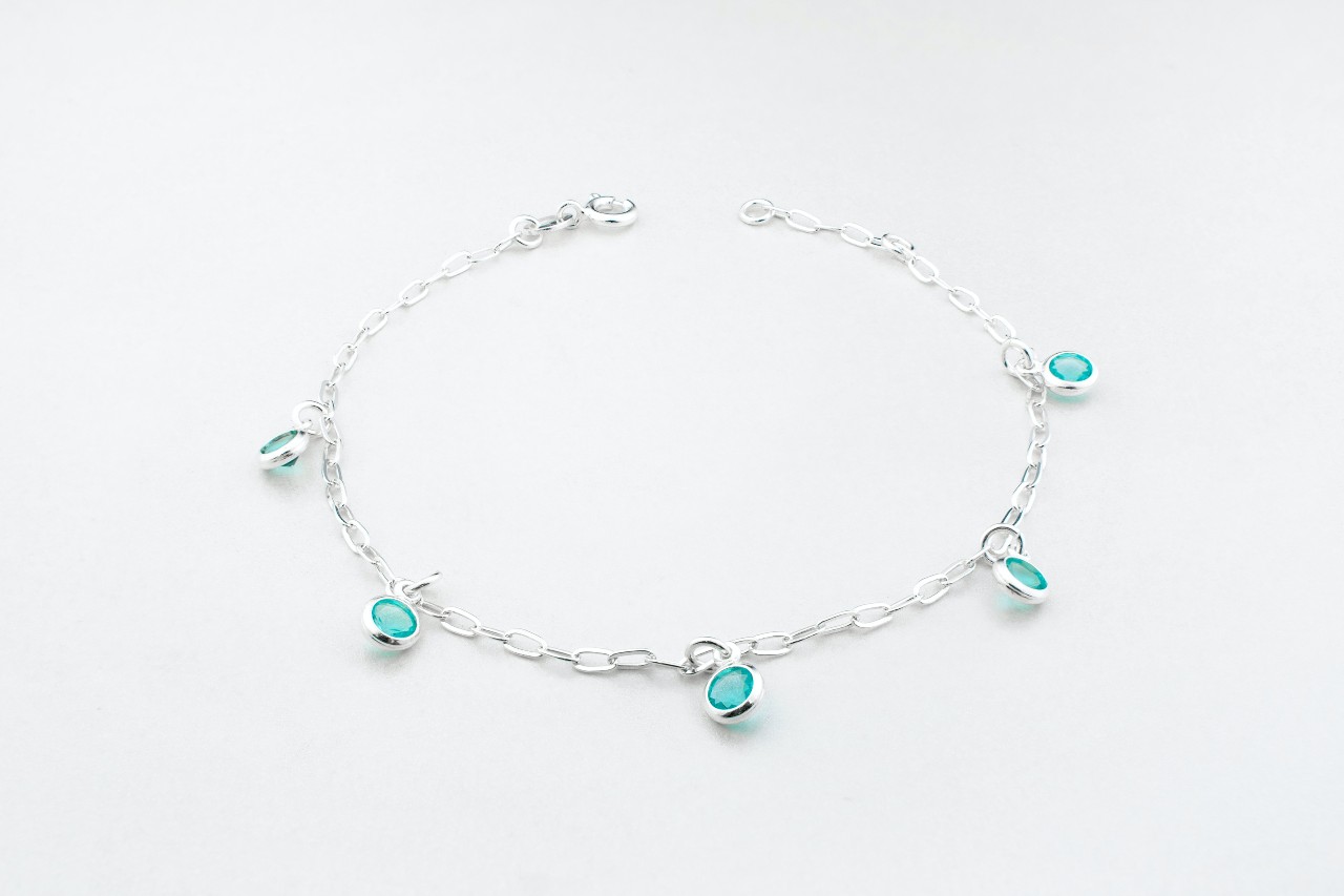 a silver chain bracelet featuring station set blue gemstones