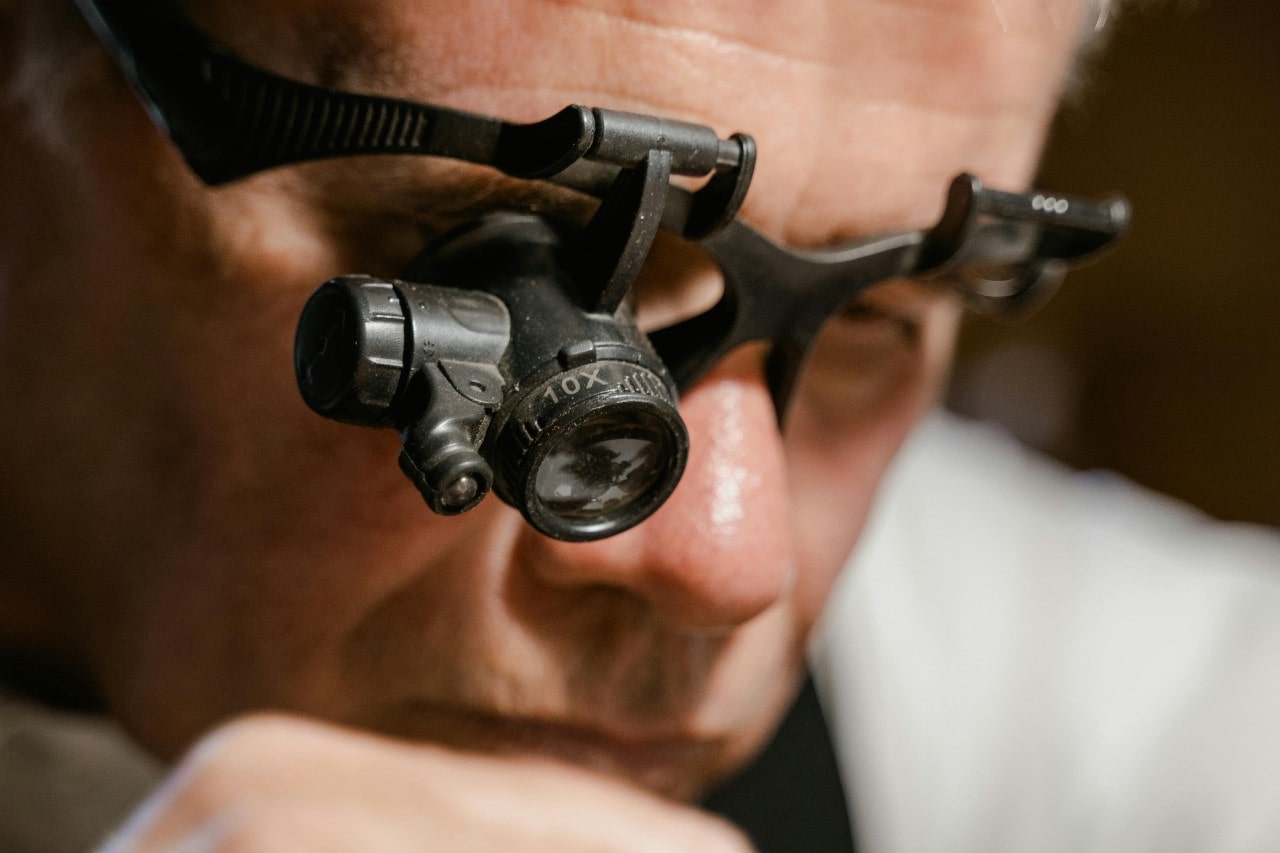 A close-up of a jeweler wearing a magnifying headset as he performs an appraisal. A close-up of a jeweler wearing a magnifying headset as he performs an appraisal.