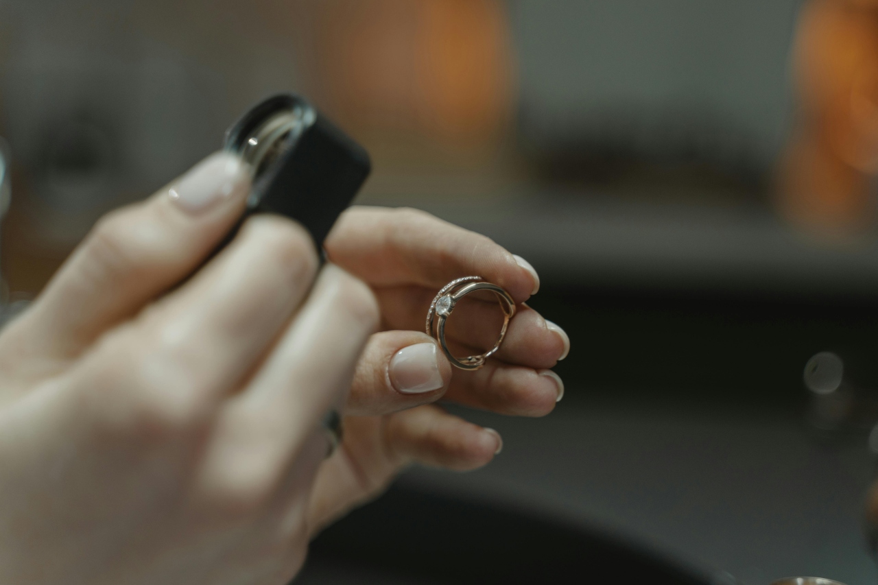A close-up of a jeweler’s hand as they examine a split shank diamond ring through a loupe. A close-up of a jeweler’s hand as they examine a split shank diamond ring through a loupe.