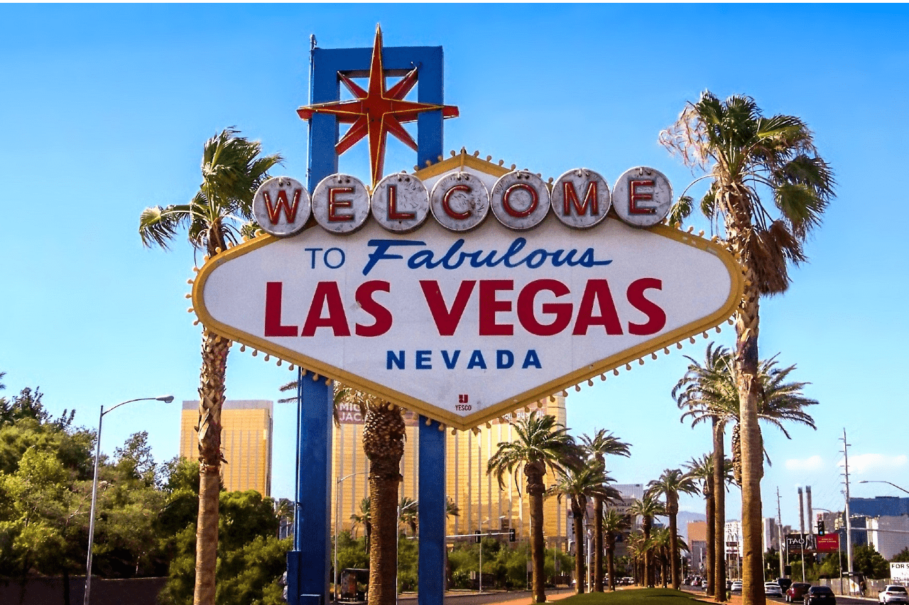 A view of the iconic “Welcome to Fabulous Las Vegas Nevada” sign, framed by palm trees on a sunny day.