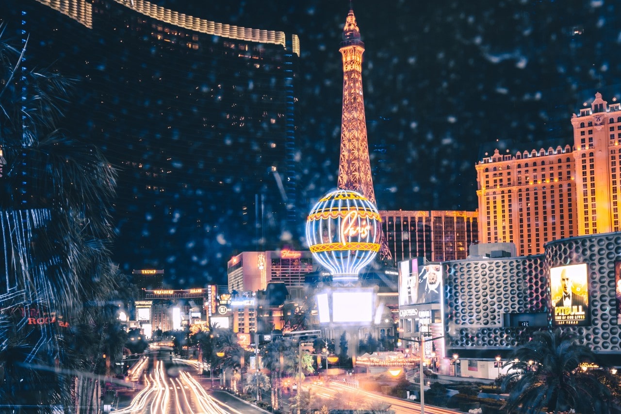A view of the Las Vegas Strip at night, spectacularly lit by nearby buildings and monuments.