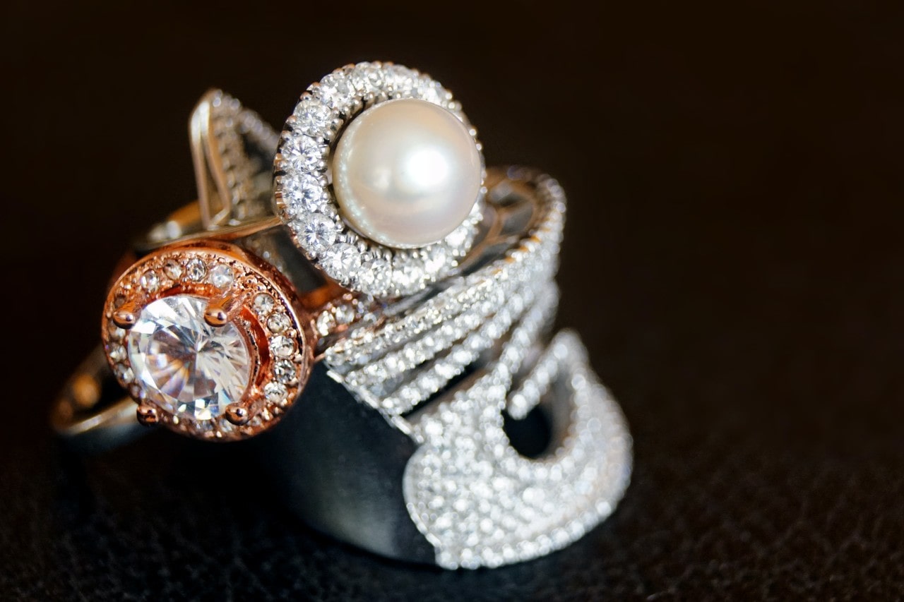 A close-up of multiple opulent gold rings, each adorned with sparkling diamonds.